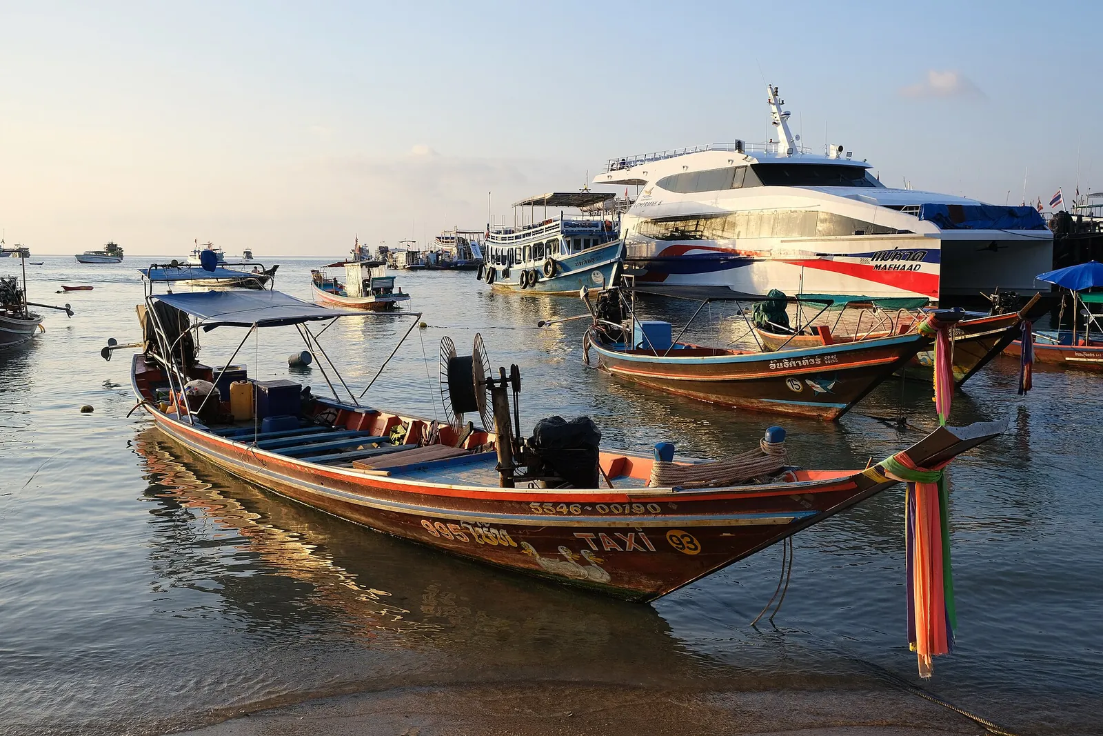 Longtail and ferry boats moored at Mae Haad beach at sunset