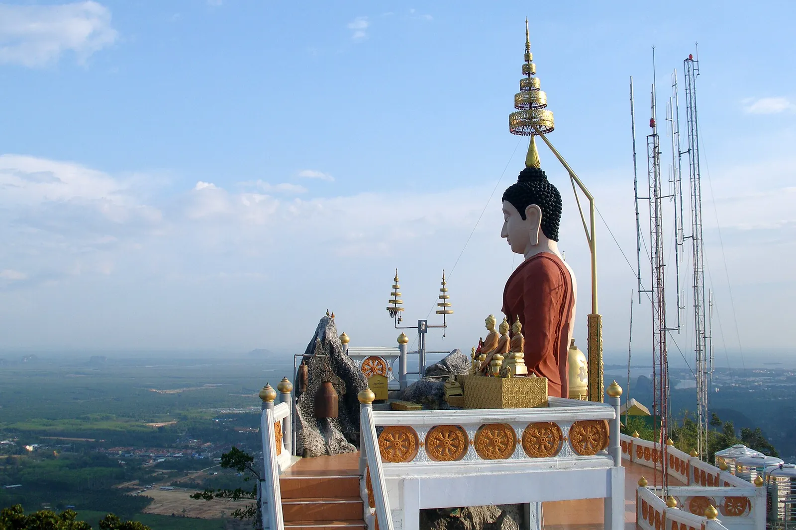 A golden seated Buddha and stupa on the hilltop of the Tiger Cave Temple above the Krabi plain