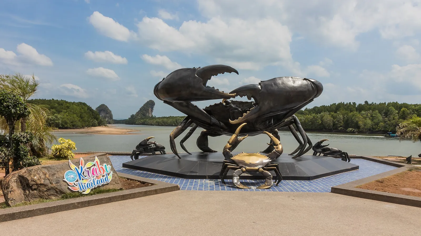 A large crab sculpture on the riverfront of Krabi Town with limestone hills behind