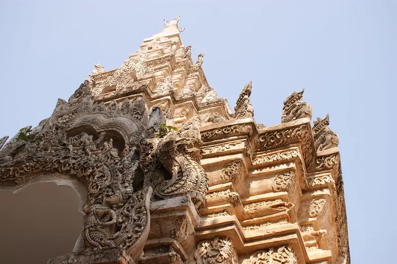 The ornate stucco entrance gate of Wat Phra That Lampang Luang against a pale sky
