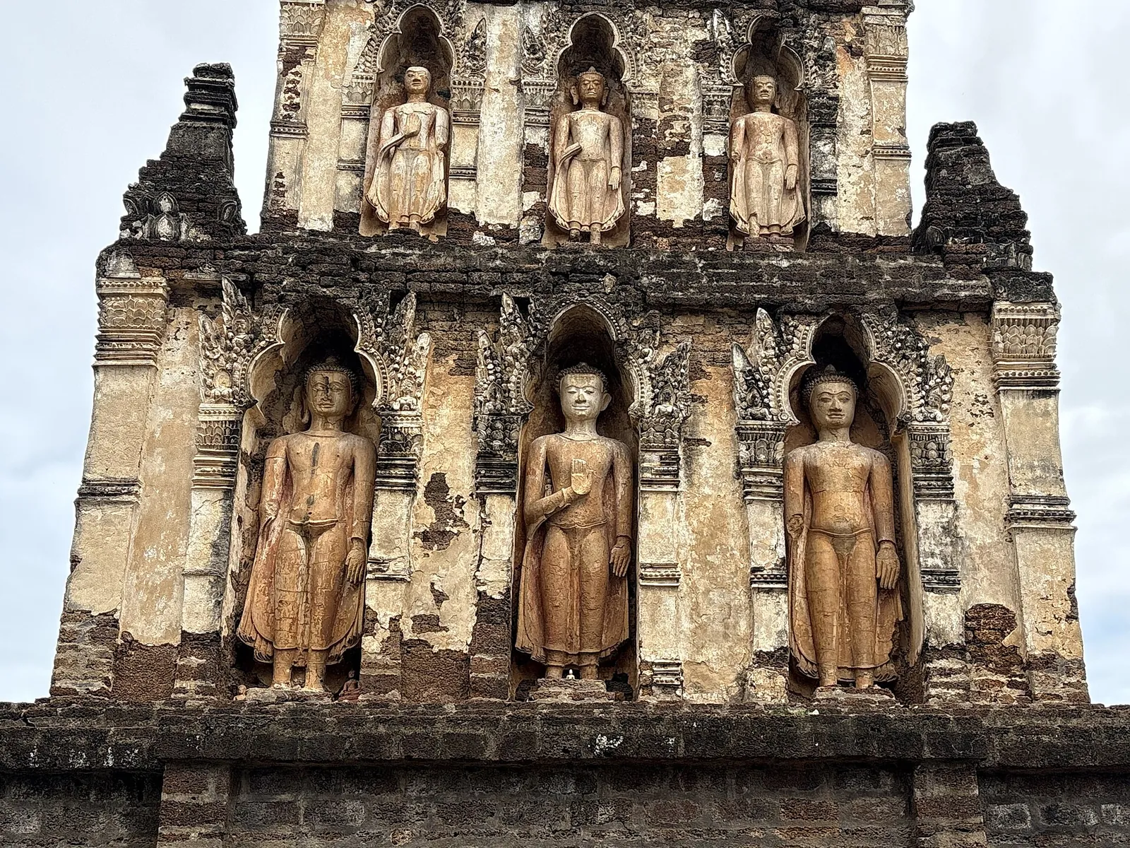 Standing stucco Buddha images in niches on the old brick chedi of Wat Chamthewi