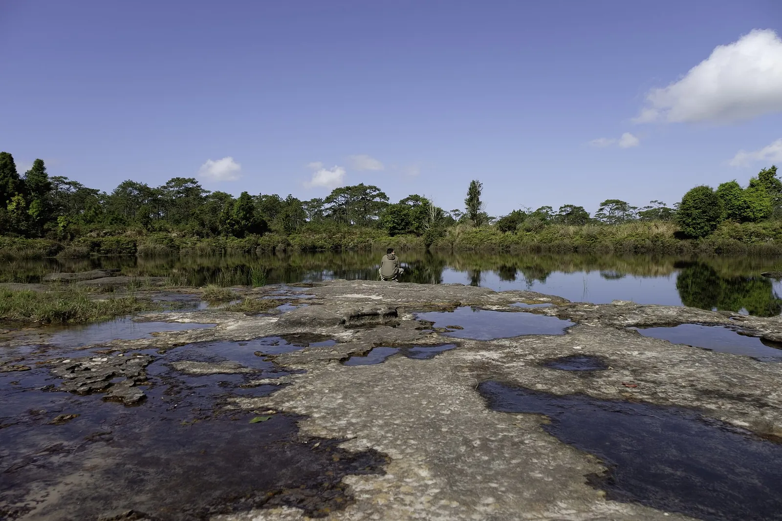 A shallow rocky pond on the sandstone plateau of Phu Kradueng under a blue sky