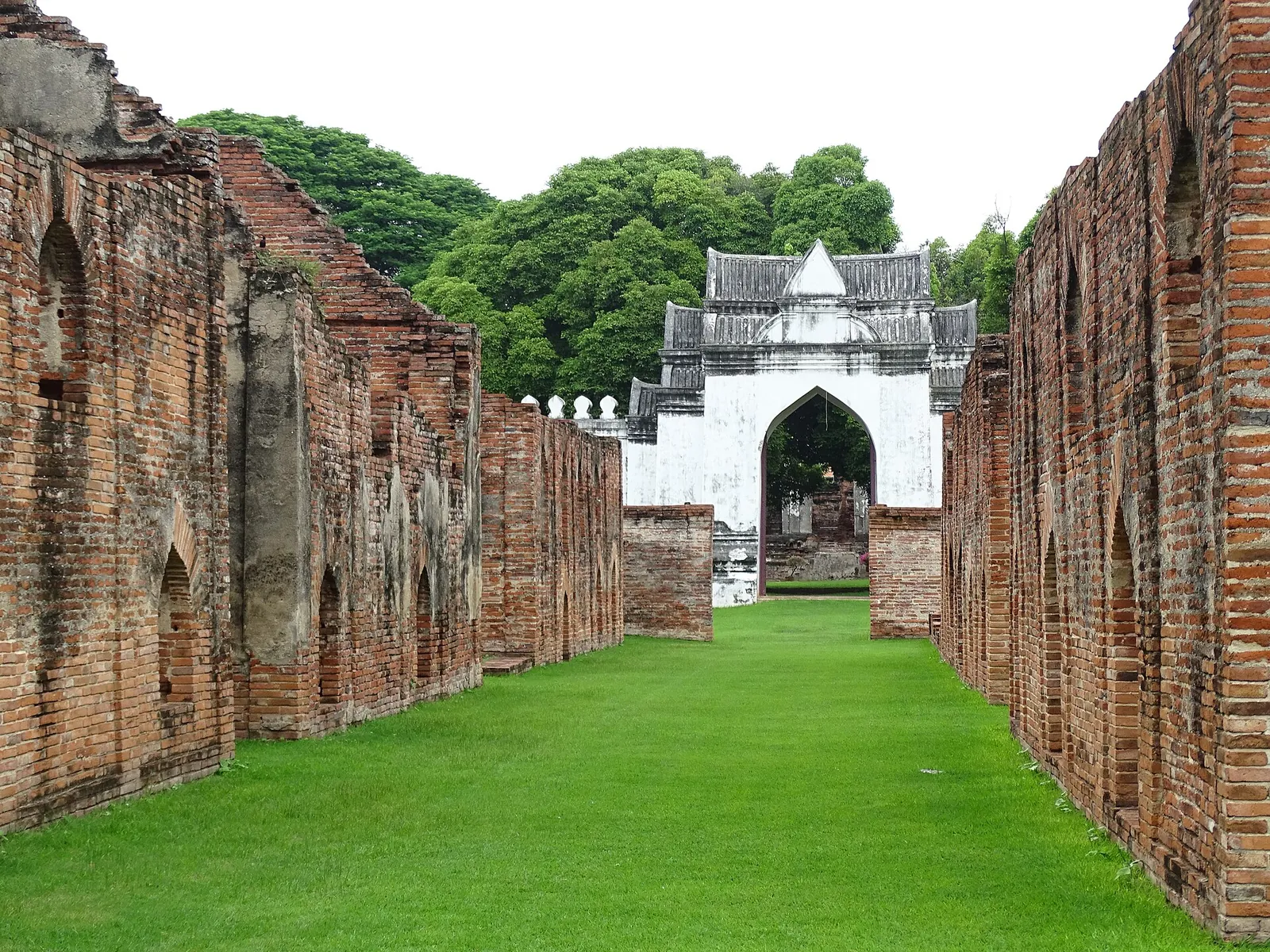 Lange Ziegelmauern führen zu einem weißen Tor in König Narais Palast in Lopburi