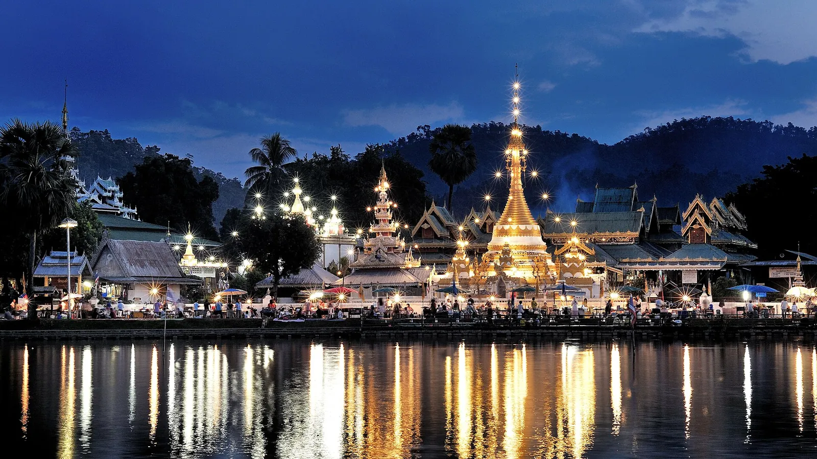 Podświetlone chedi w stylu birmańskim Wat Chong Klang i Wat Chong Kham odbite o zmierzchu w jeziorze Nong Chong Kham