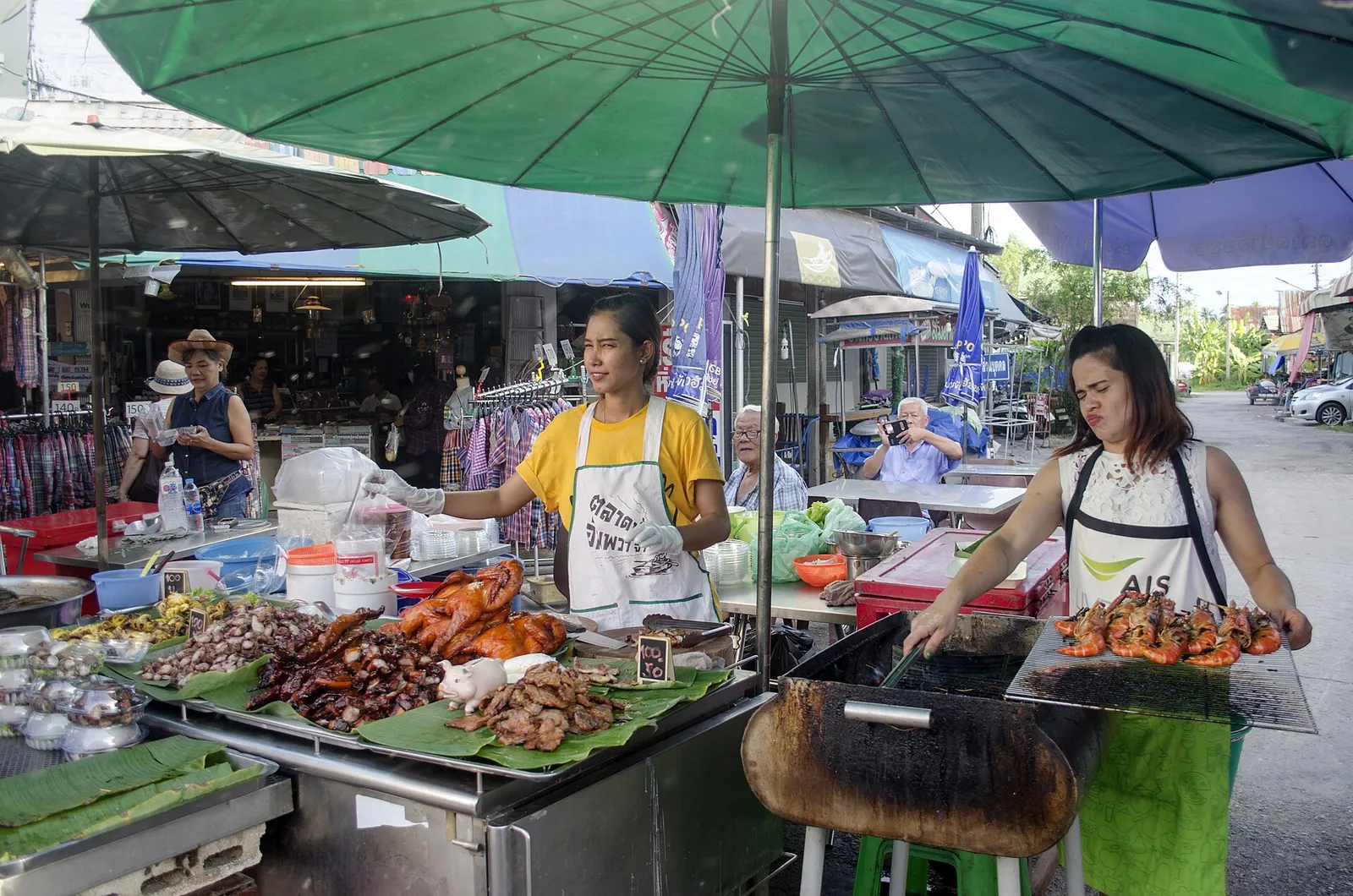 Venditori che cucinano in uno stallo del mercato all'aperto di Amphawa