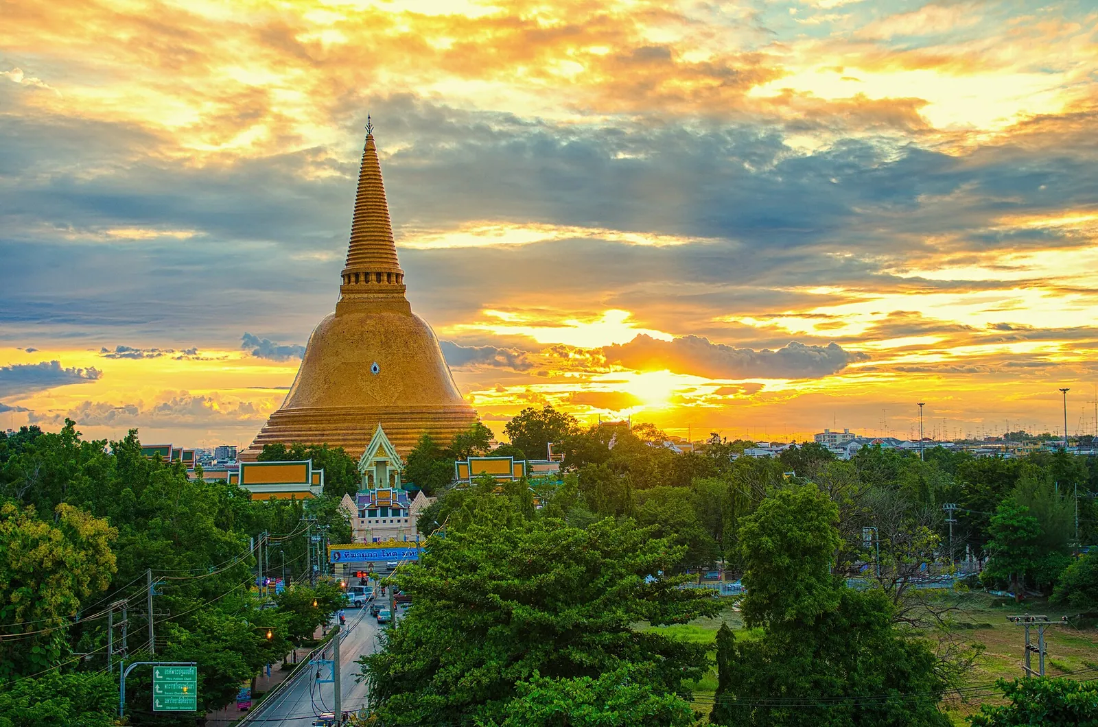 Zlatá věž Phra Pathom Chedi nad stromy Nakhon Pathomu při západu slunce