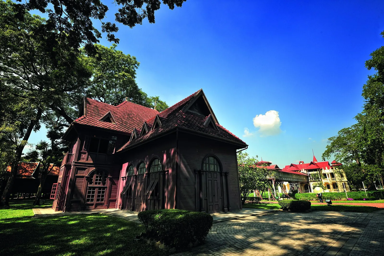 Tmavě červená dřevěná rezidence v zahradách paláce Sanam Chandra pod modrou oblohou