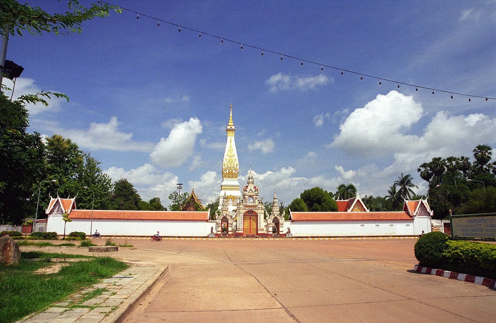 The walled compound of Wat Phra That Phanom with its golden spire and a wide forecourt