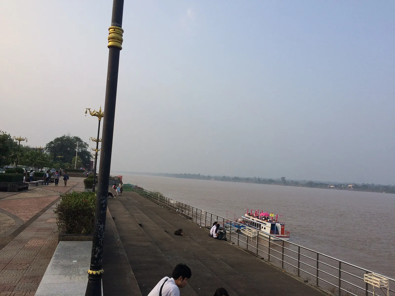 Boats moored by the riverside walkway on the Mekong at Nakhon Phanom