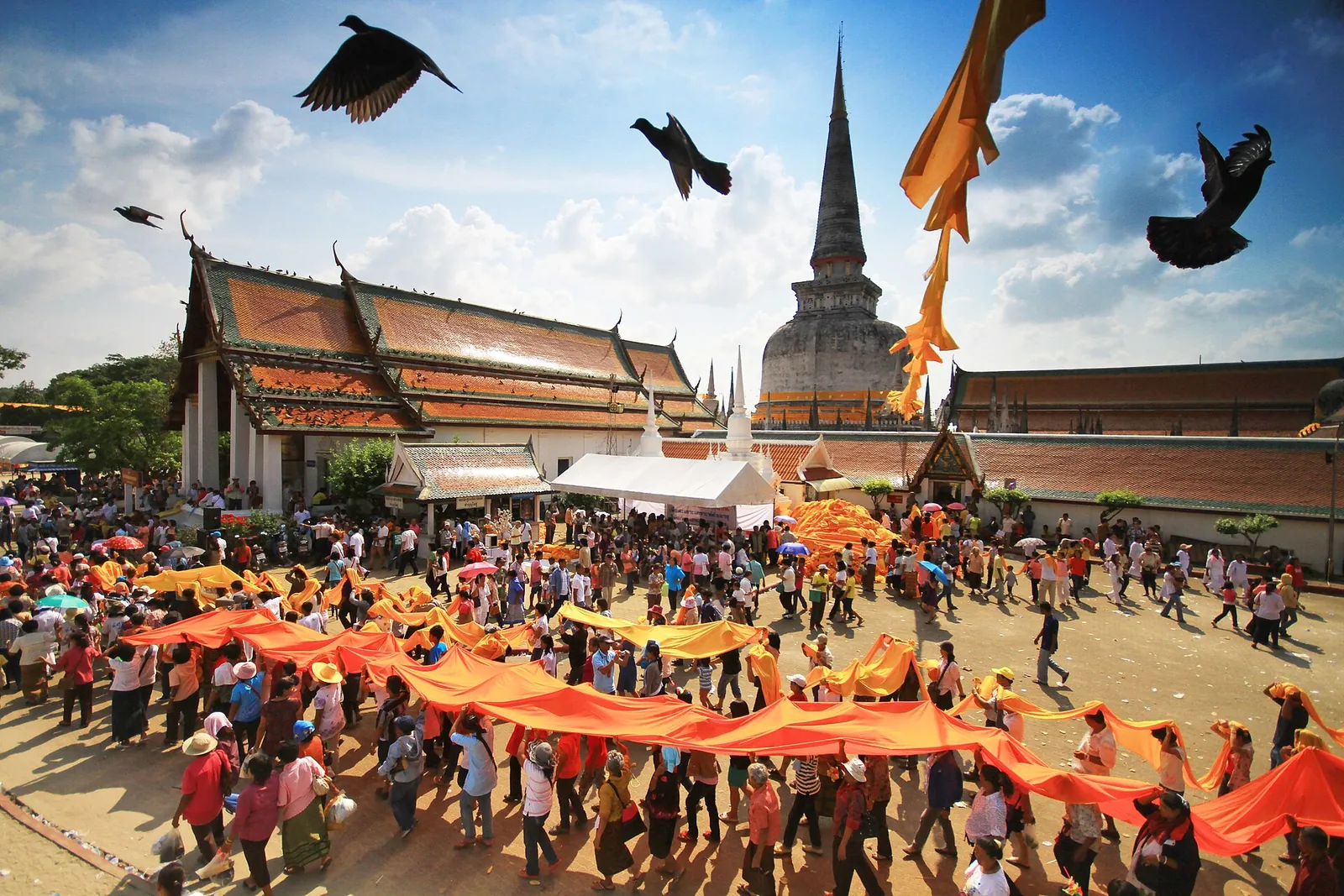 Pilgrims carrying a long orange cloth in procession around the great chedi