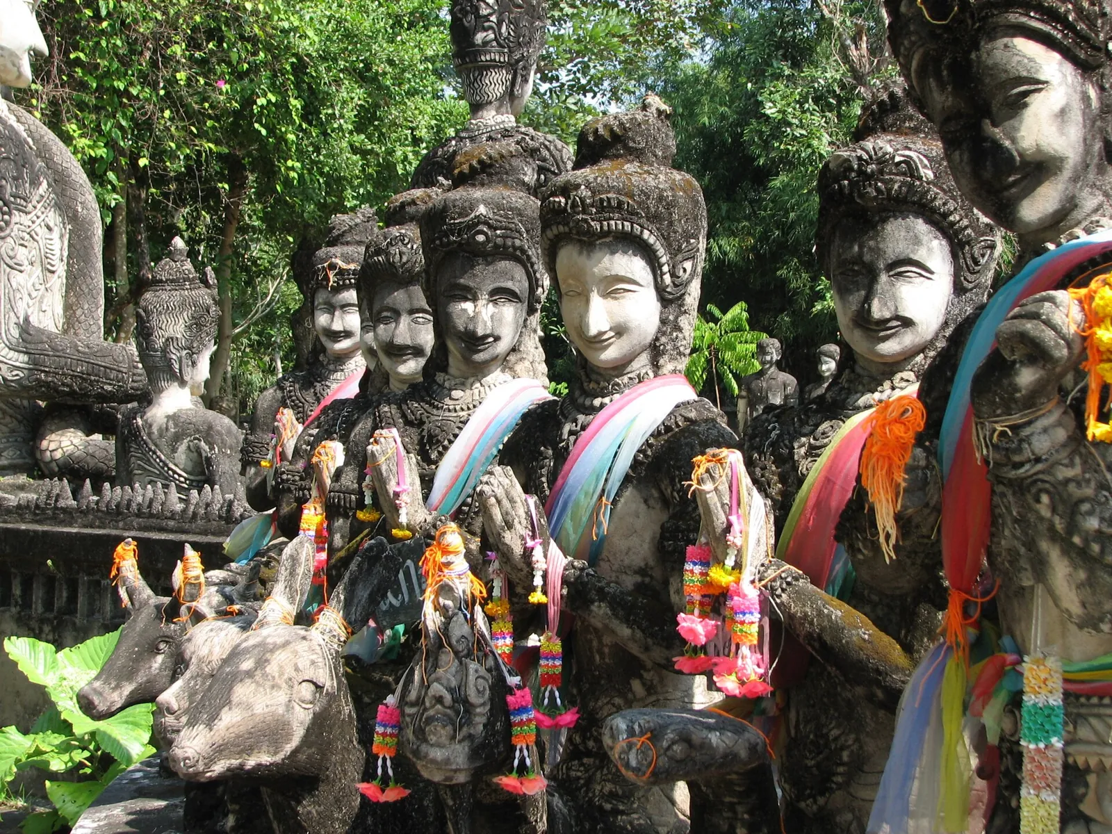 Rows of concrete figures draped with colourful scarves and garlands at Sala Kaew Ku