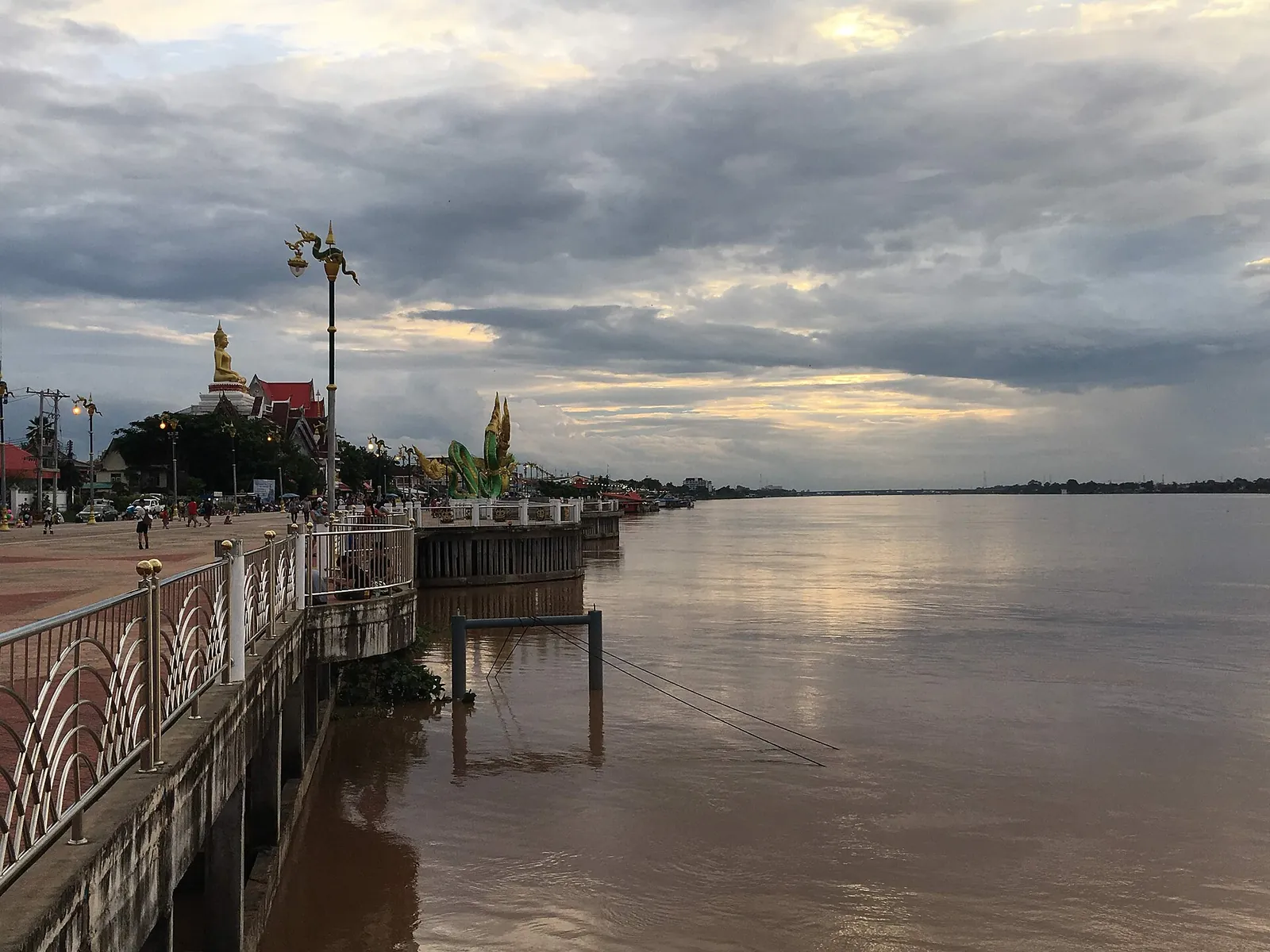 The riverside promenade of Nong Khai beside the wide brown Mekong under clouds