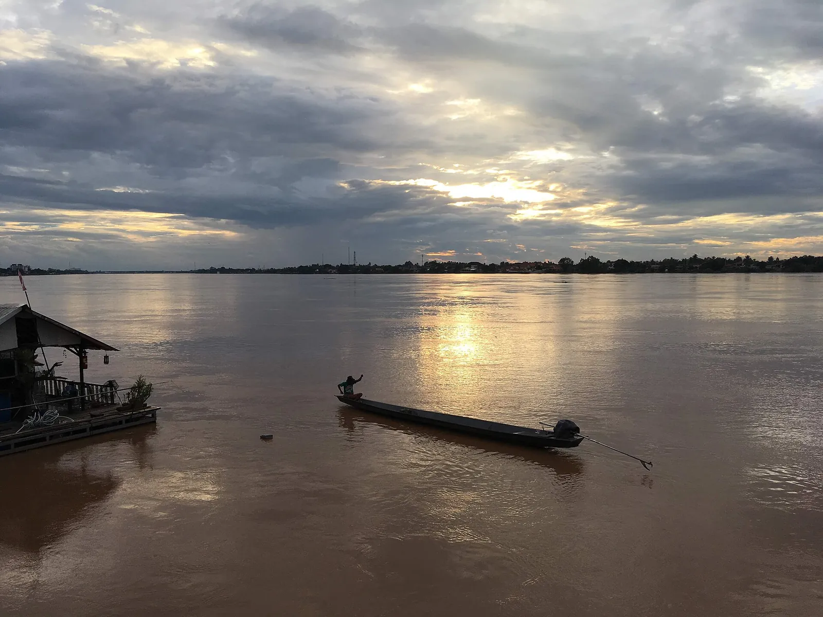 A longtail boat on the Mekong at Nong Khai under a cloudy evening sky