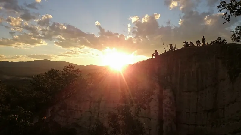 Visitors silhouetted on the ridges of Pai Canyon as the sun sets over the hills