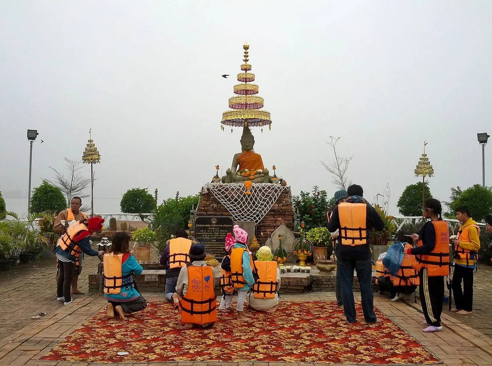 Visitantes de colete salva-vidas no templo da ilha, Wat Tilokaram, no Kwan Phayao