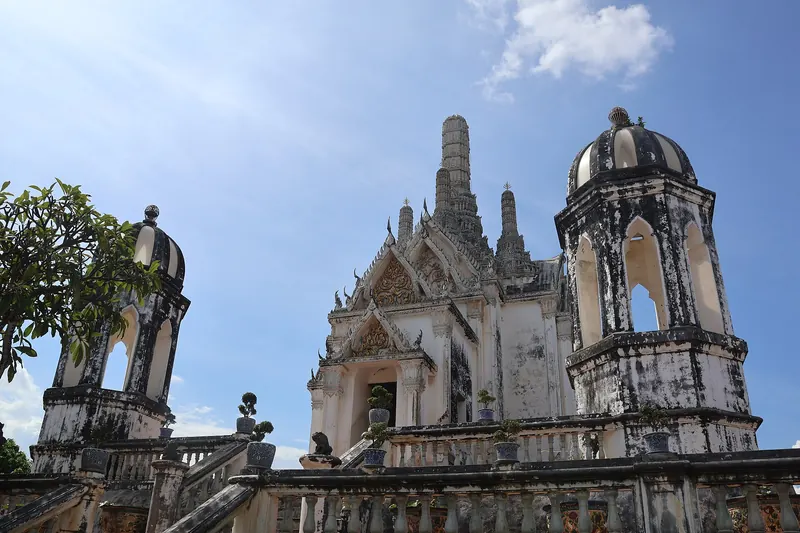 White temple buildings and a domed tower on the summit of Khao Wang under a blue sky