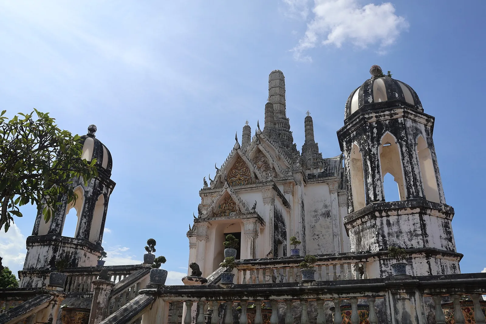 White temple buildings and a domed tower on the summit of Khao Wang under a blue sky