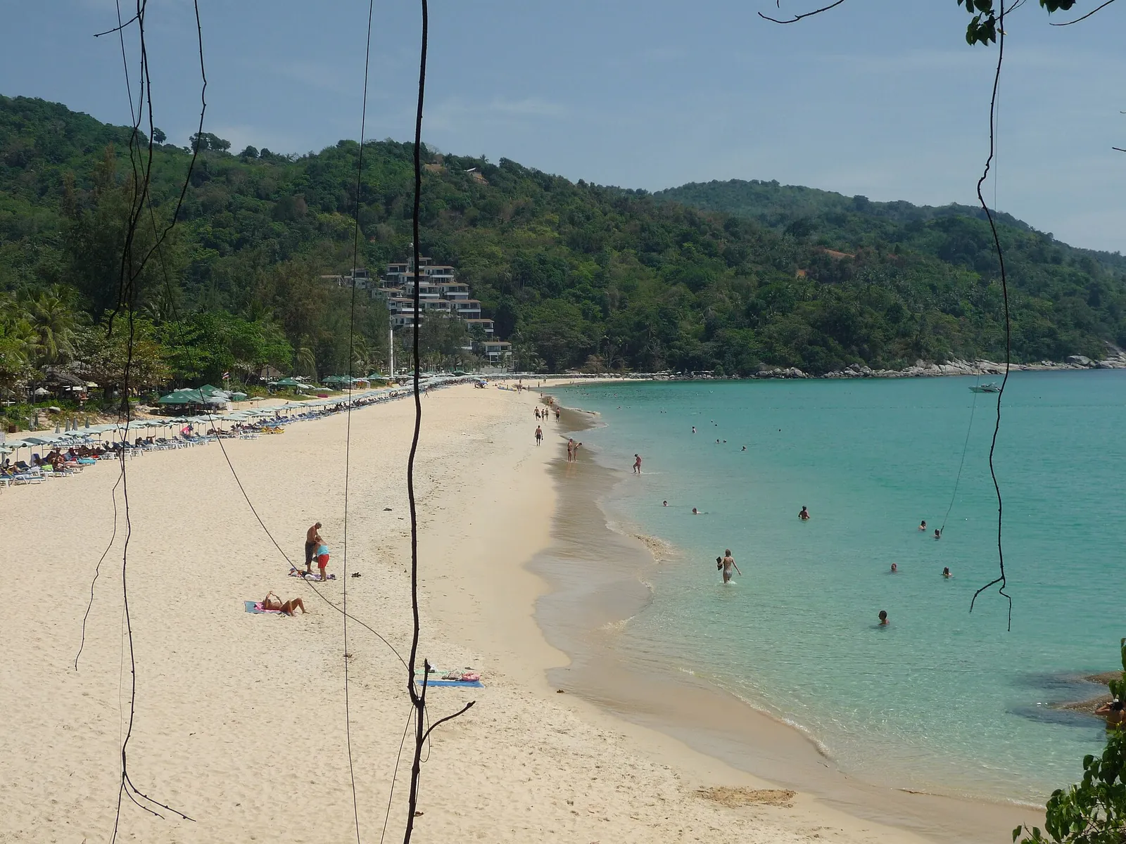 The curve of Kata Beach with turquoise water and forested hills