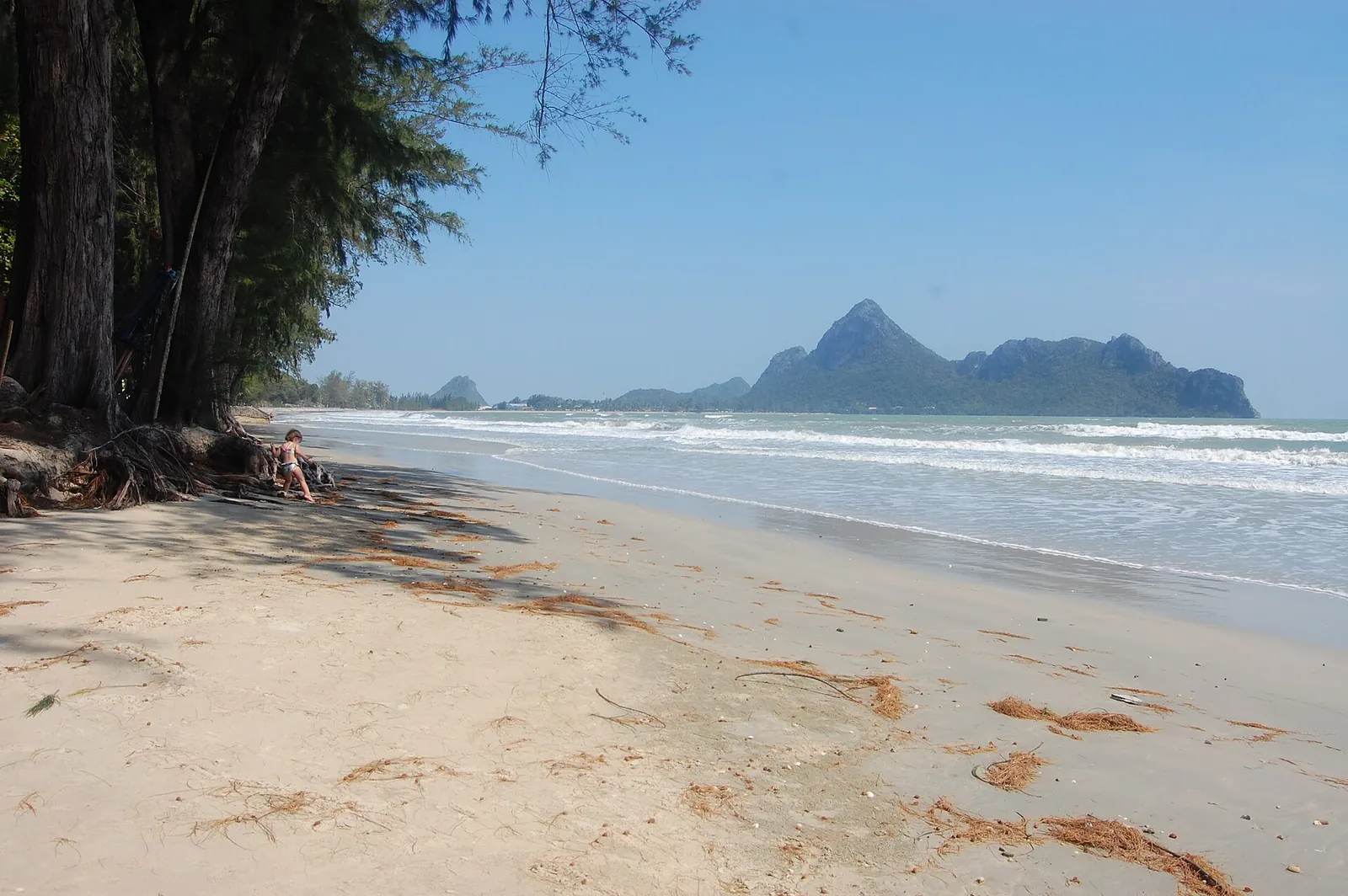 Ein ruhiger Sandstrand, der sich in Ao Manao zu Kalksteininseln hin schwingt