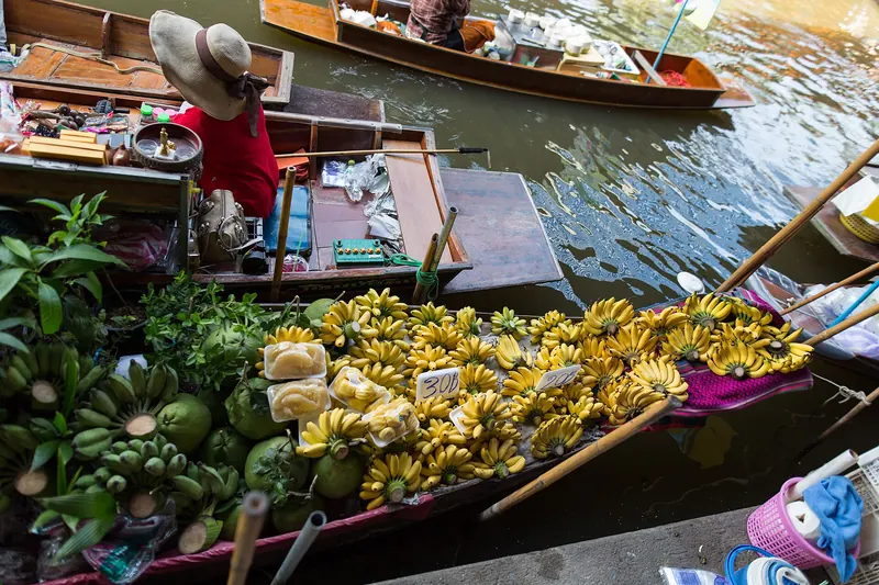 A vendor's rowing boat piled with bananas and fruit on a canal at Damnoen Saduak