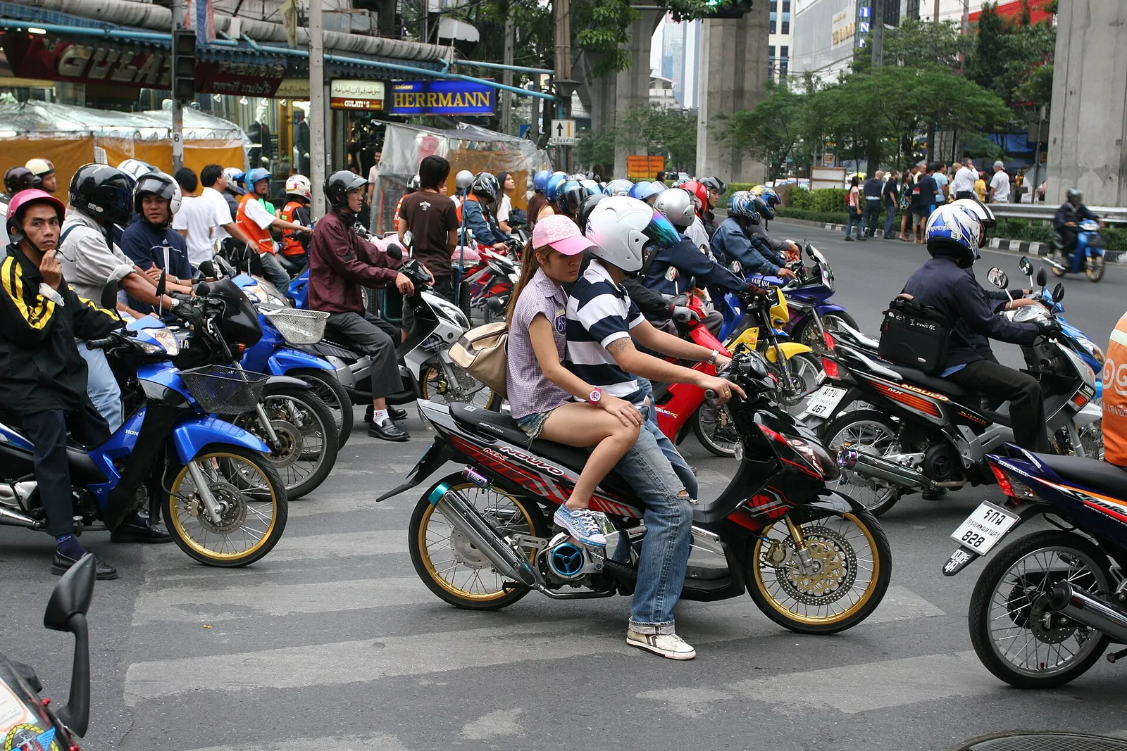 Motocykly a jezdci na rušné křižovatce Bangkoku