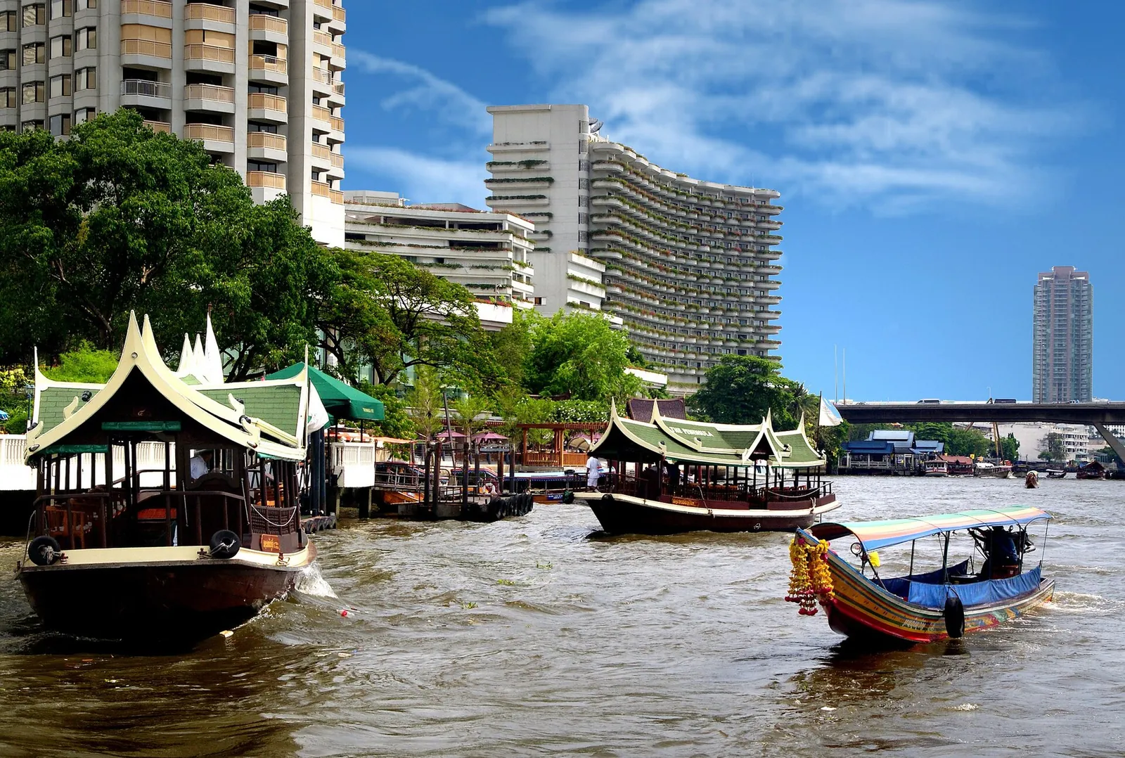 Lodě kotvící podél bangkokské řeky Chao Phraya pod modrou oblohou