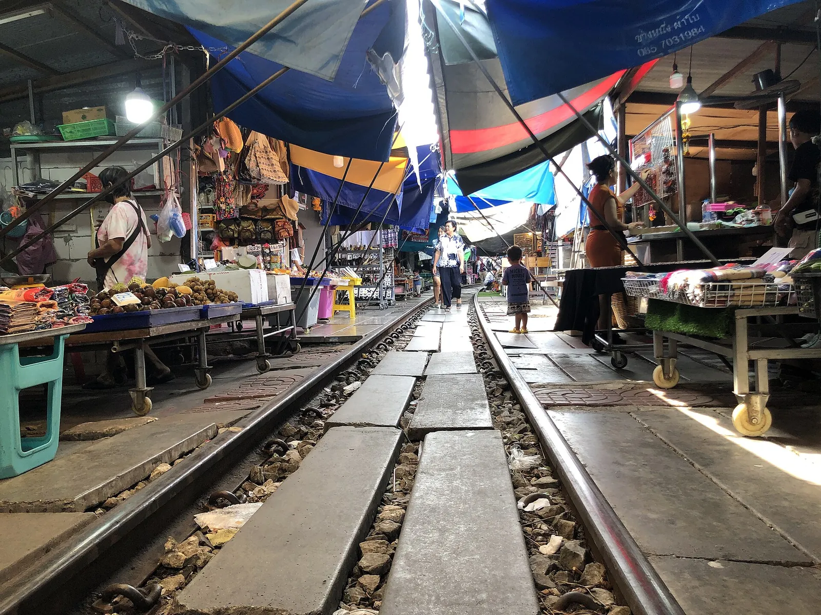 Market stalls and awnings lining both sides of the railway track at Maeklong market