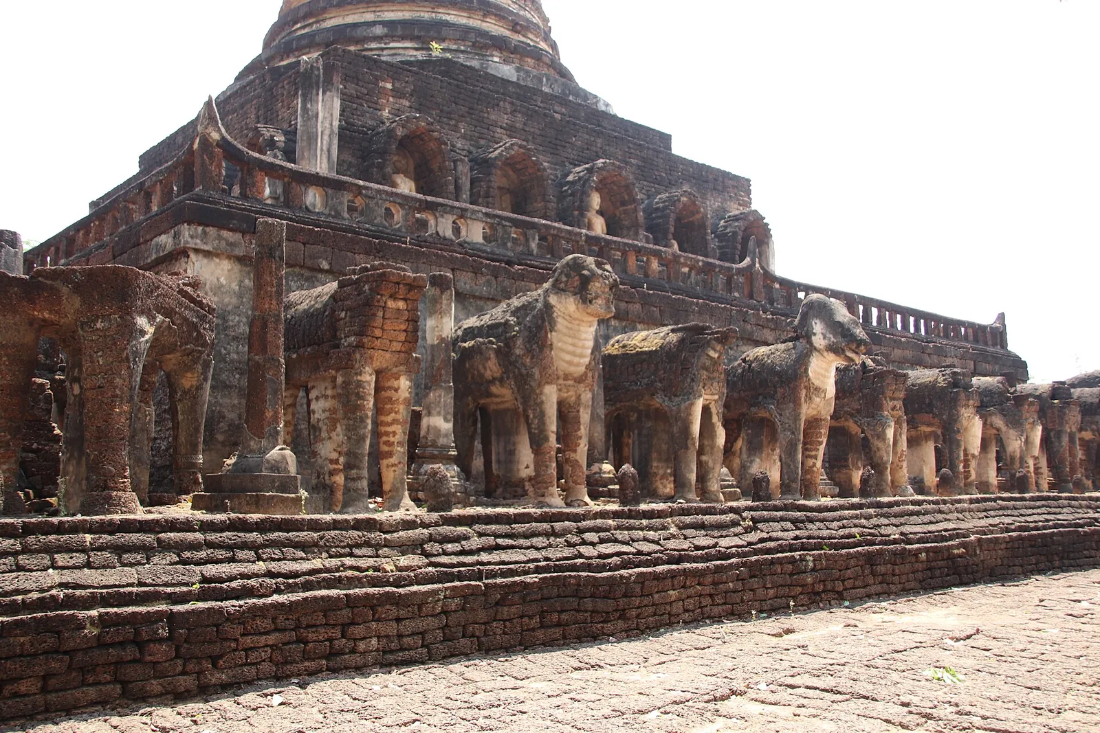 Rows of laterite and stucco elephants around the square base of Wat Chang Lom