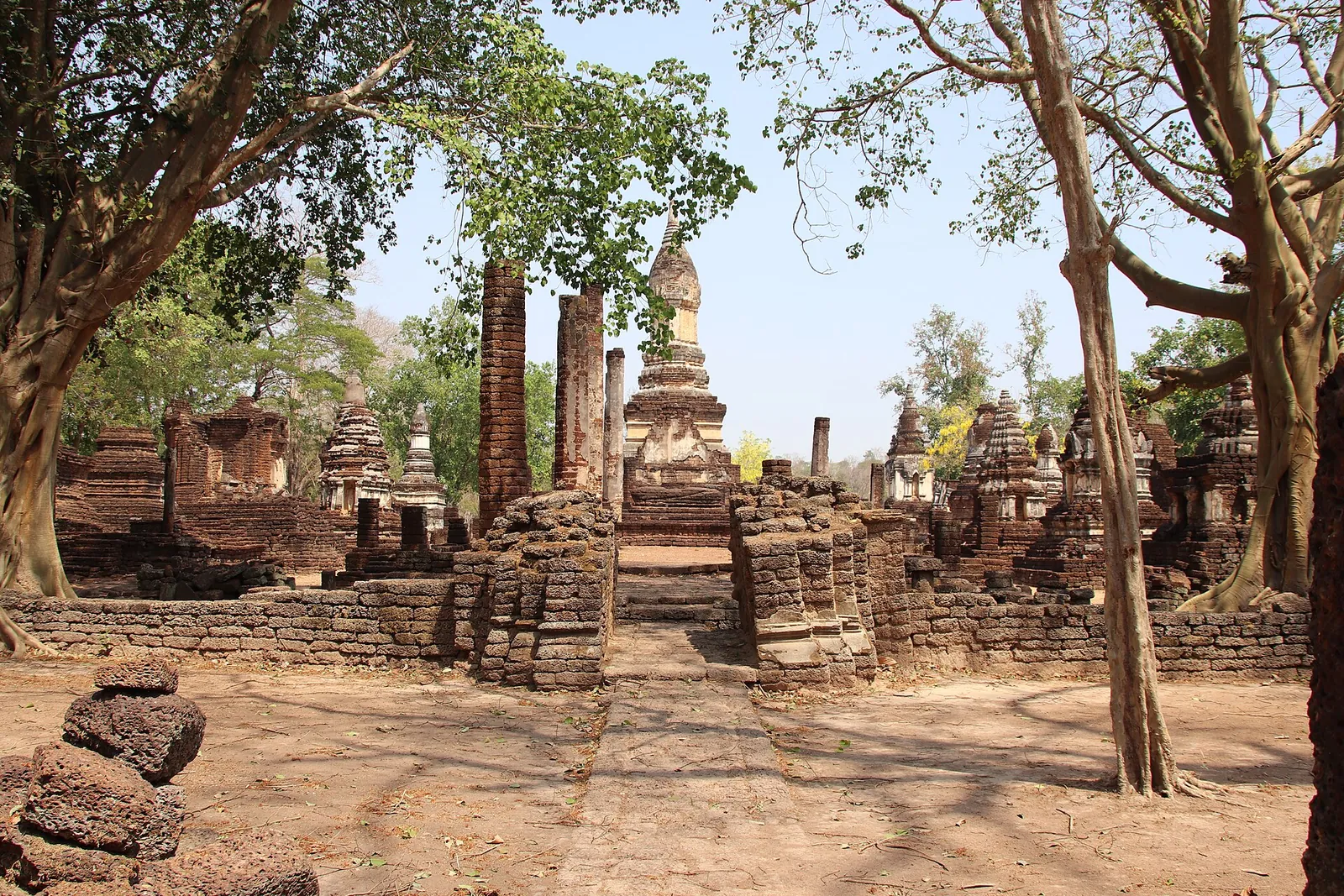 Rows of small brick chedis and pillars among trees at Wat Chedi Chet Thaeo