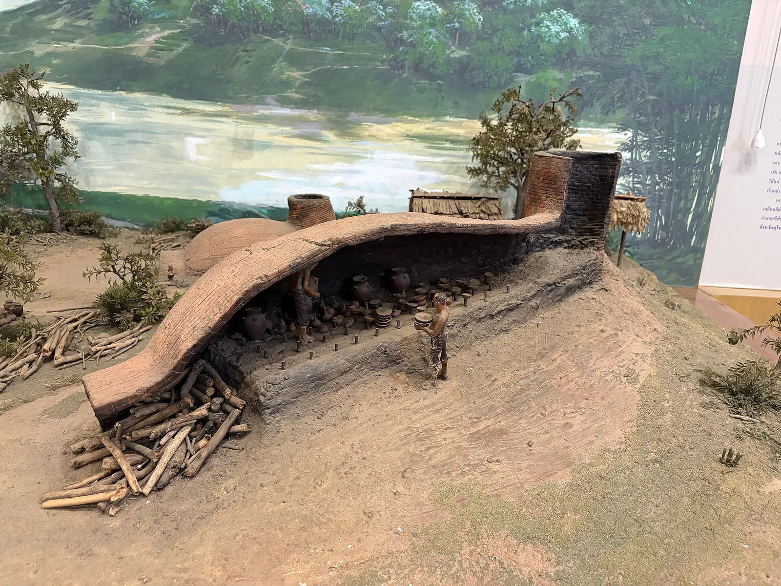 A museum scale model of a Sangkhalok ceramic kiln with stacked firewood