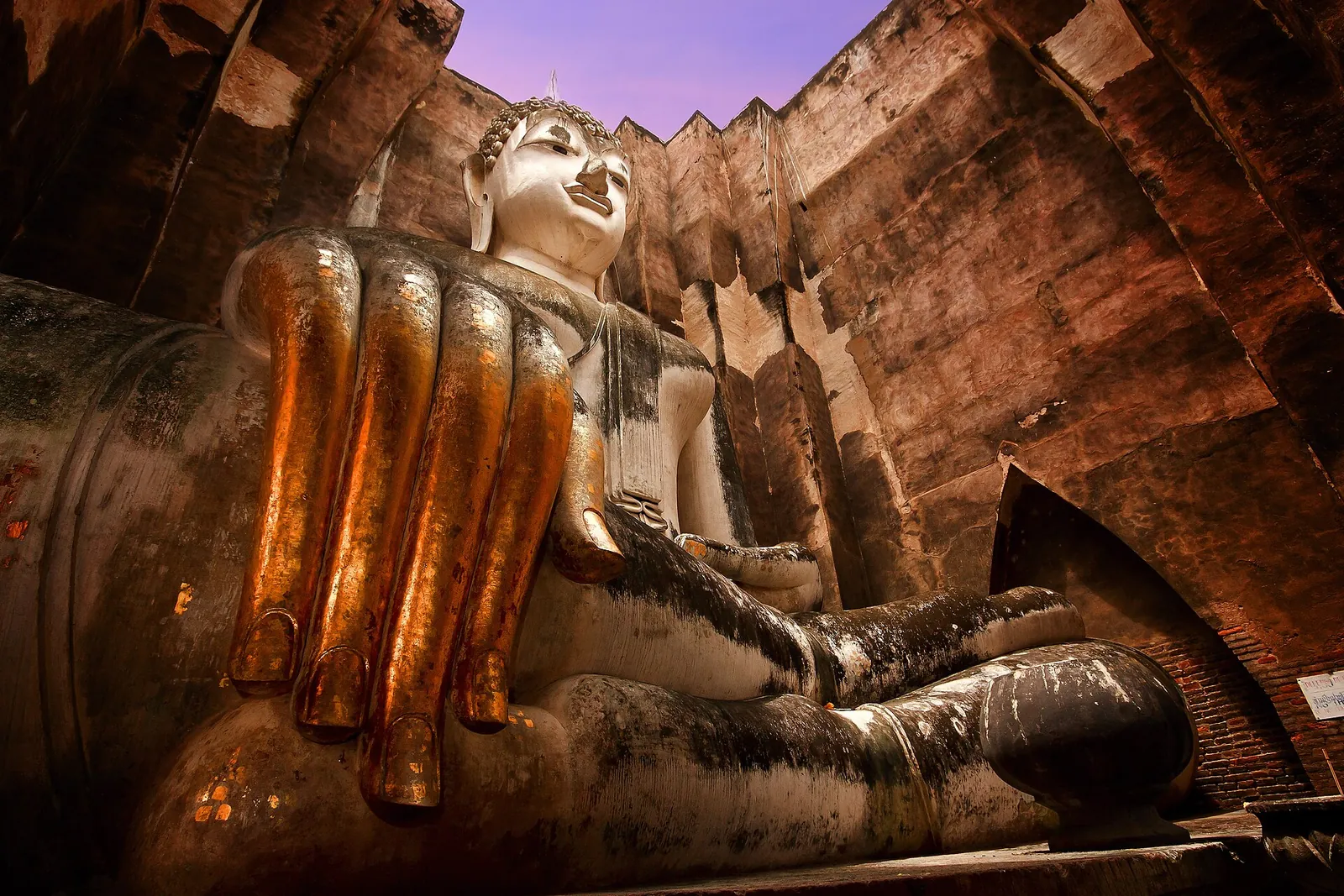 The giant stucco hand and face of the seated Phra Achana Buddha inside the tall mondop of Wat Si Chum