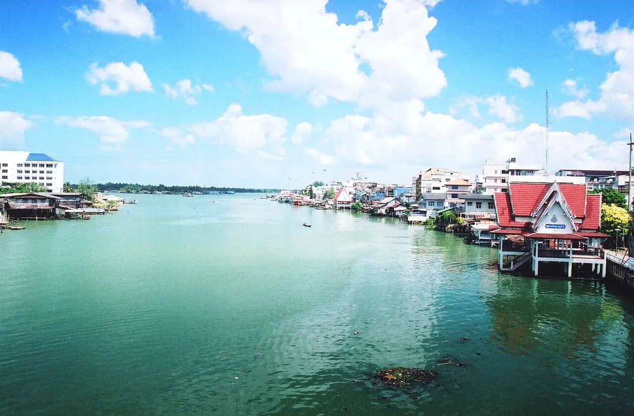 The Tapi River waterfront of Surat Thani with houses and a temple roof