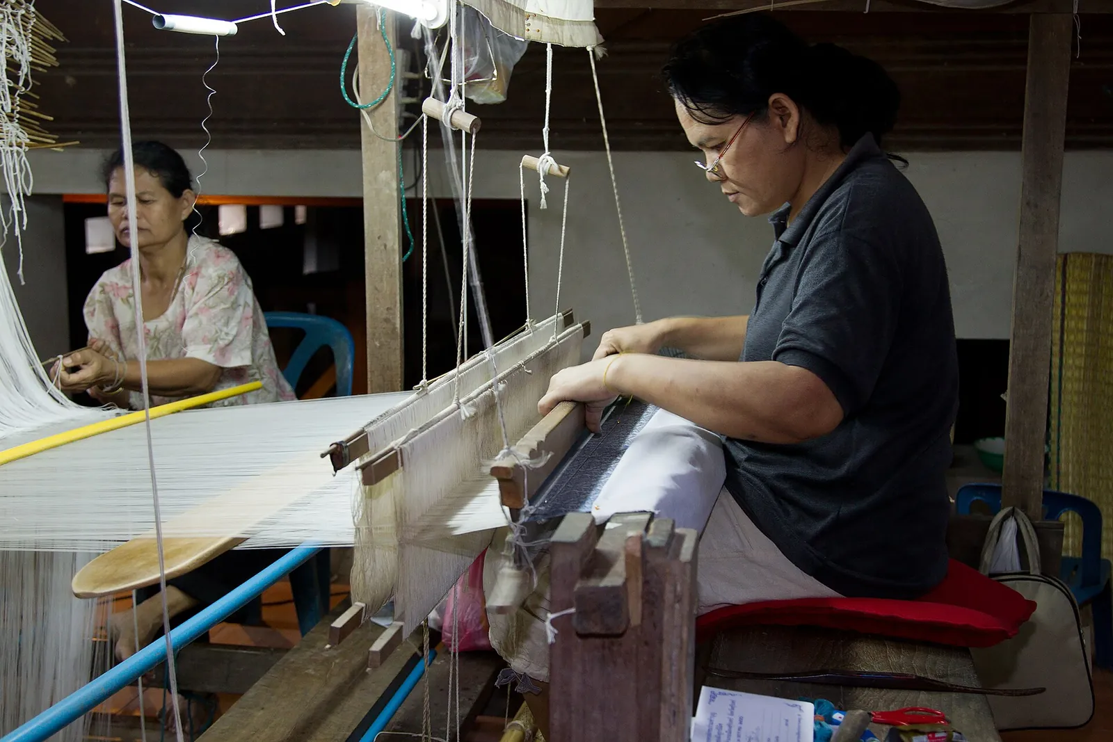 A weaver working at a wooden loom in a silk workshop at Ban Tha Sawang