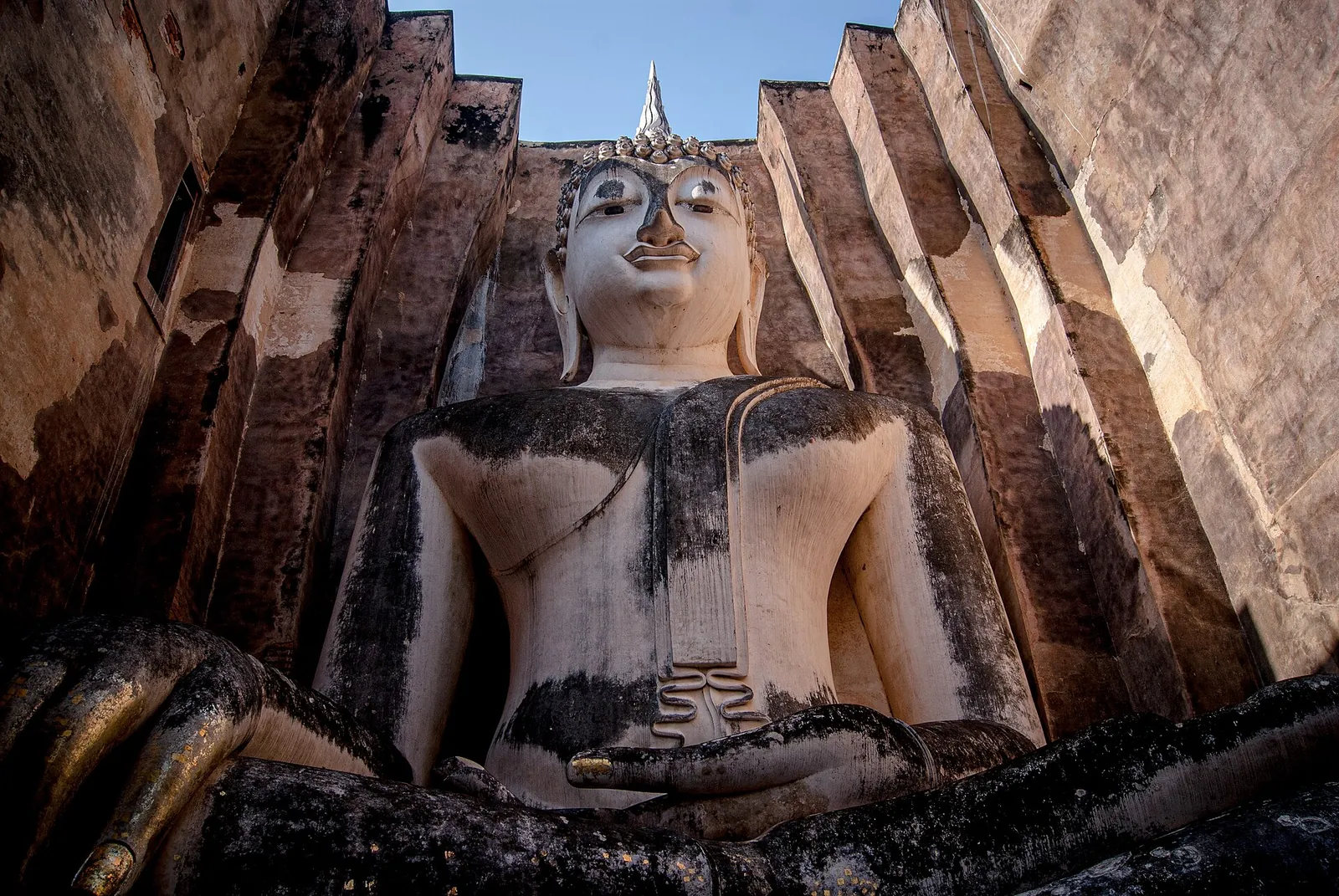 Velký sedící Buddha uvnitř cihlových zdí Wat Si Chum v Sukhothai