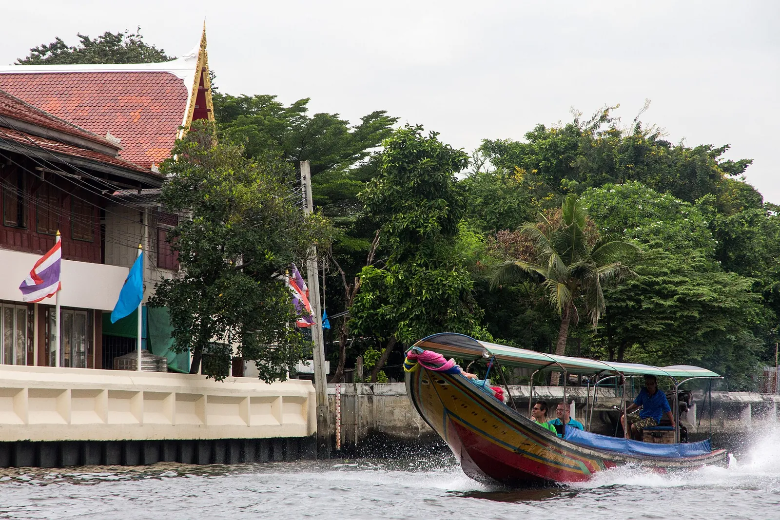Dlouhá loď vedle domů a chrámu na kanálu Bangkok Noi