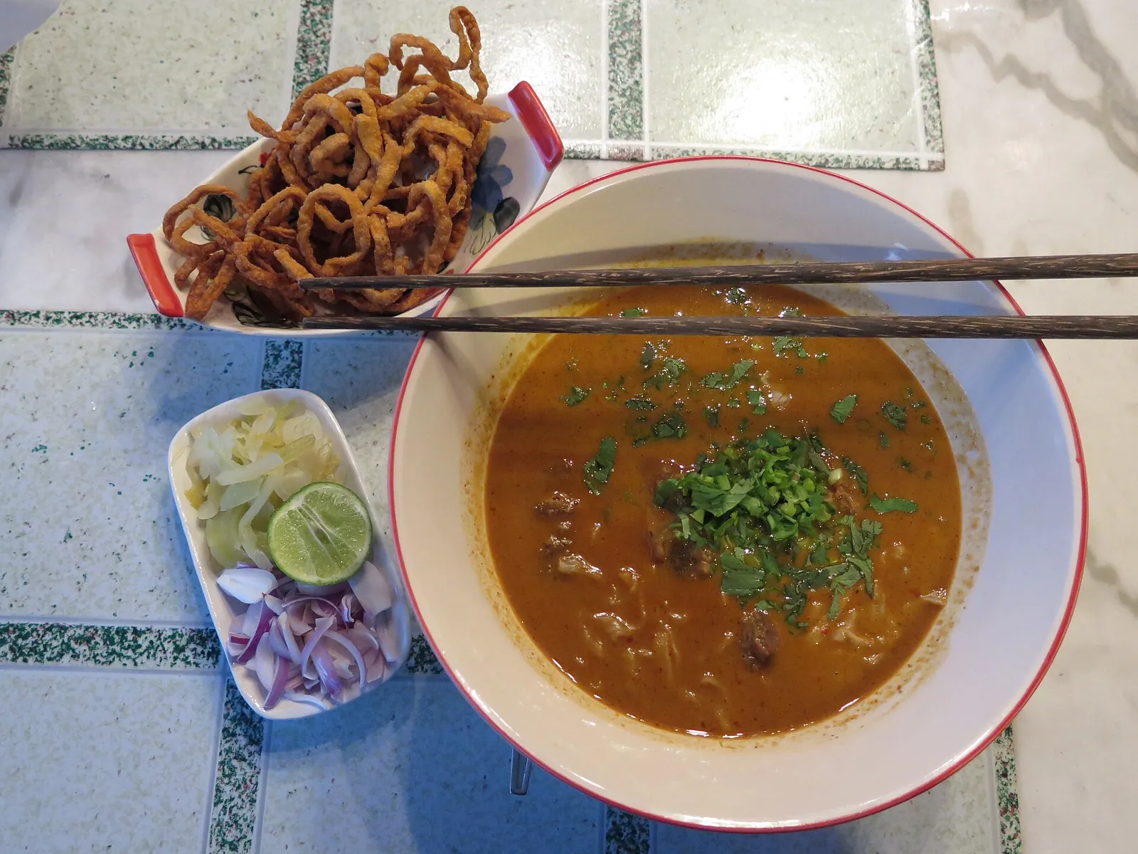 Miska khao soi s křupavými nudlemi a limetkou v Chiang Mai