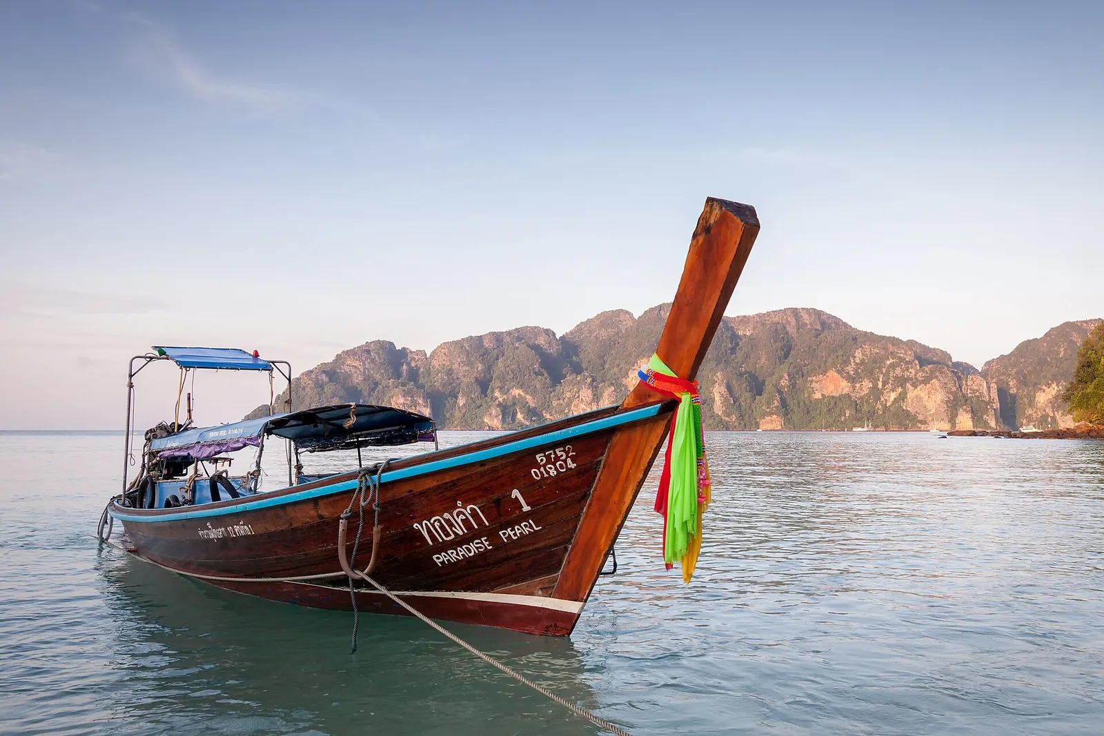A long-tail boat moored off Ko Phi Phi Don with limestone cliffs behind