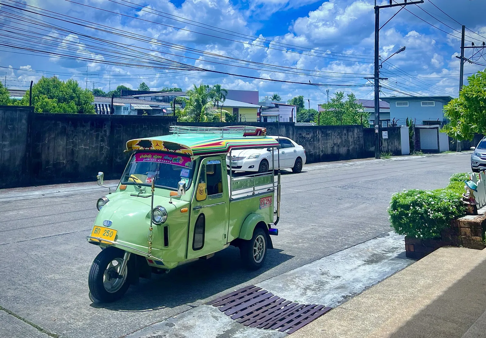 A green Trang-style tuk-tuk parked in a street of Trang town