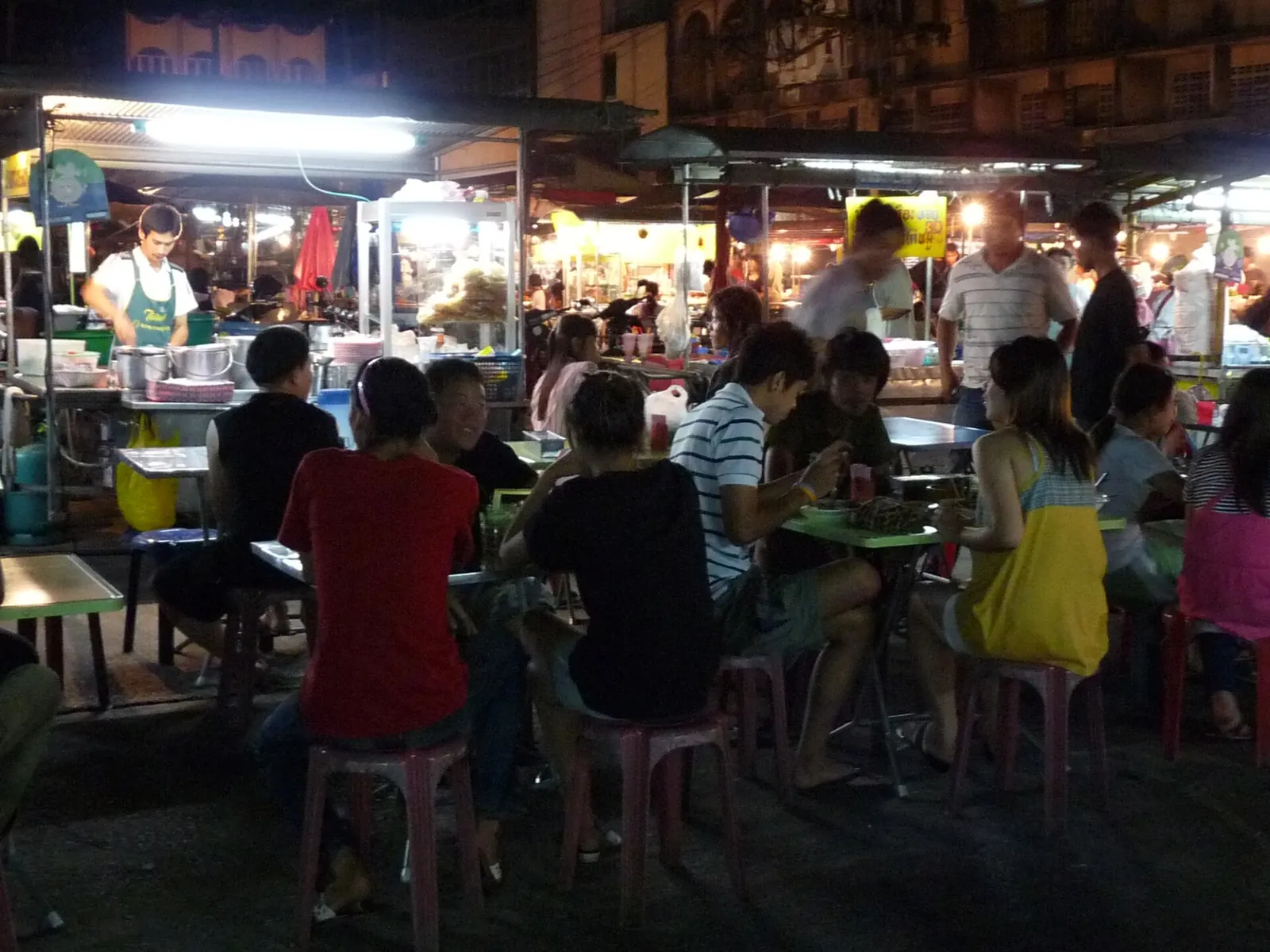Diners at plastic tables under lights at the night market in Trat town