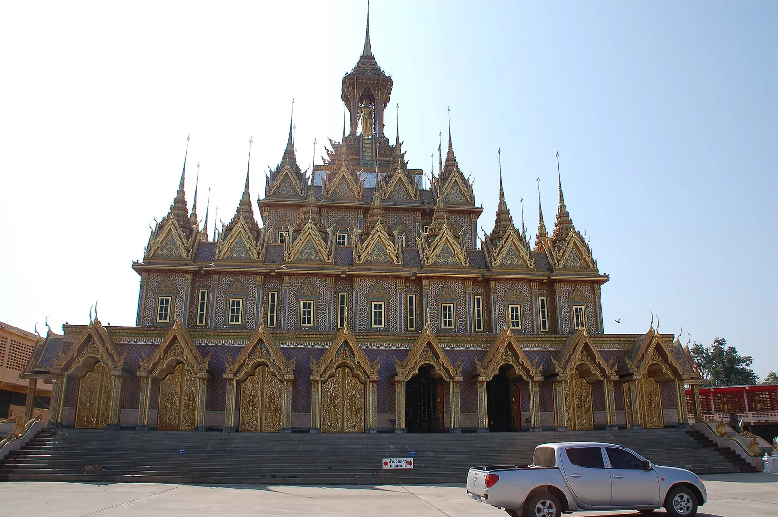 El castillo dorado de muchas agujas de Wat Tha Sung en Uthai Thani bajo un cielo pálido