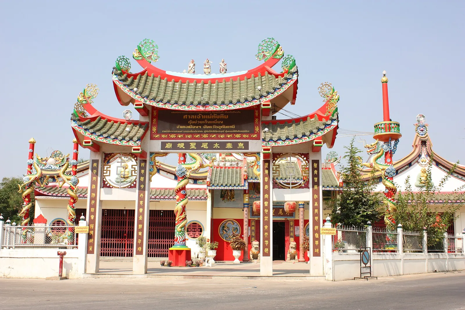 La ornamentada puerta china y los tejados de un santuario hainanés en Uthai Thani