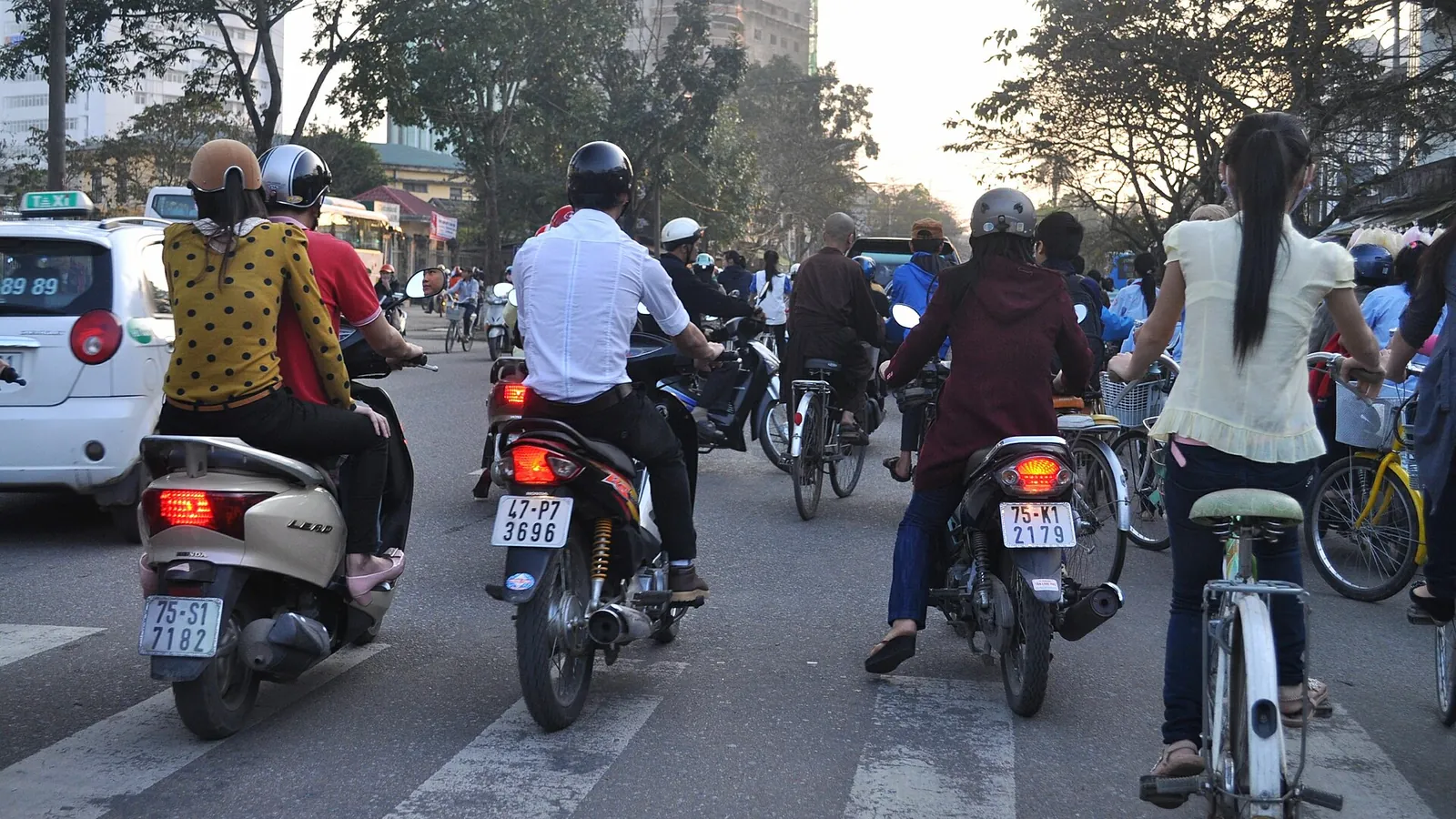 Motorbikes and bicycles filling a road crossing in Hue