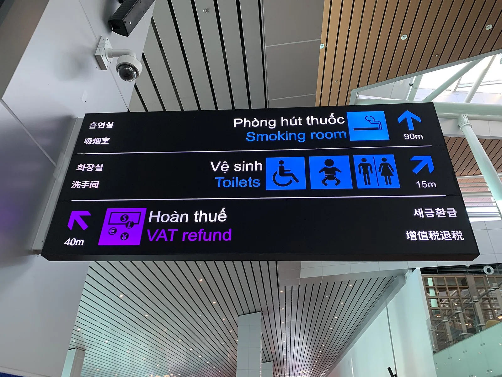 Bilingual sign at Da Nang International Airport pointing to toilets, with wheelchair, baby-change and toilet symbols