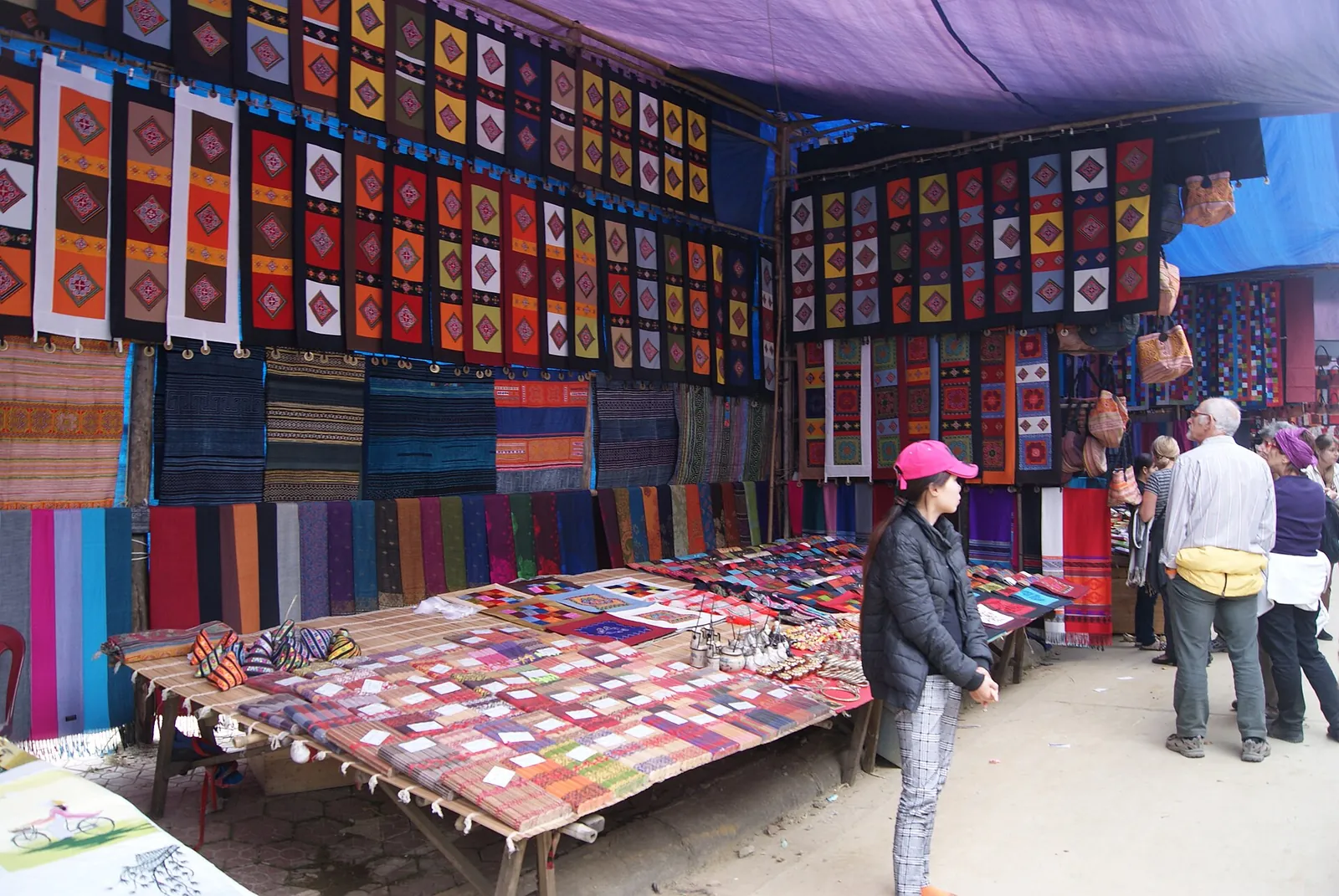 Stalls hung with colourful woven and embroidered textiles at Bac Ha Sunday market