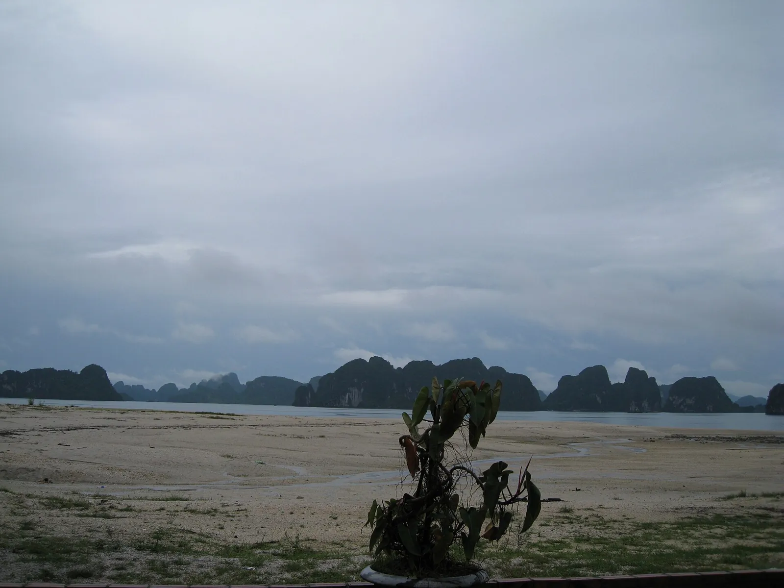 A wide sandy beach at low tide on Quan Lan Island with limestone islands on the horizon