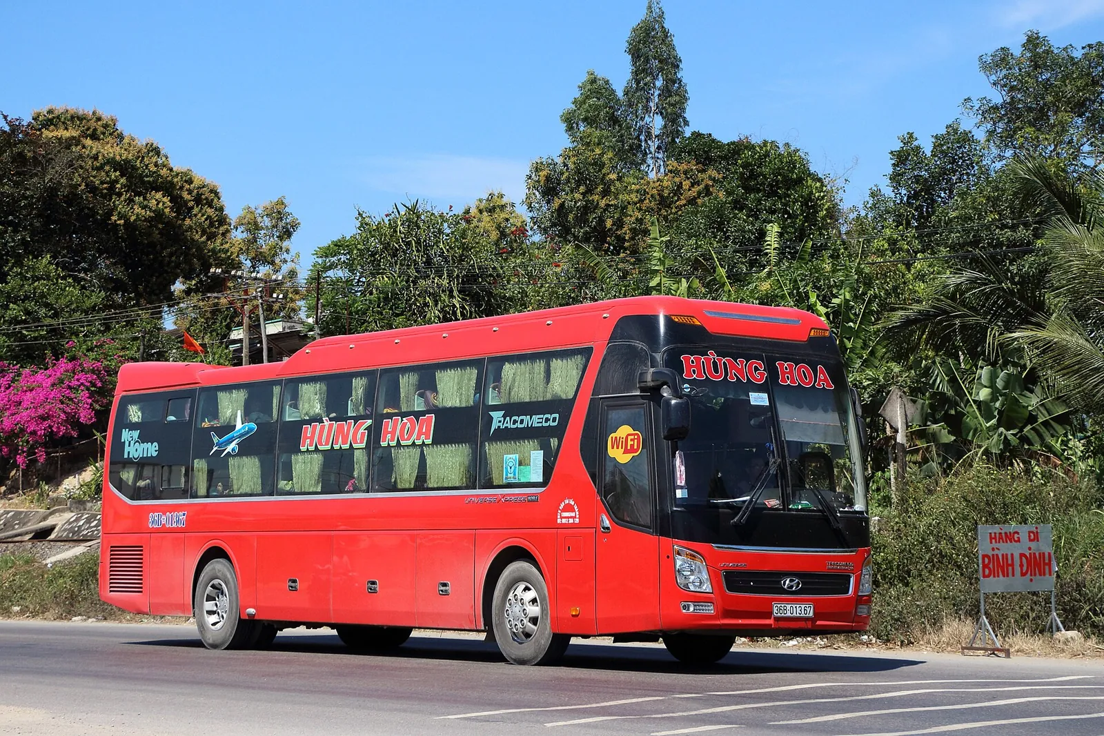 Red Tracomeco long-distance sleeper bus parked by a roadside in Vietnam