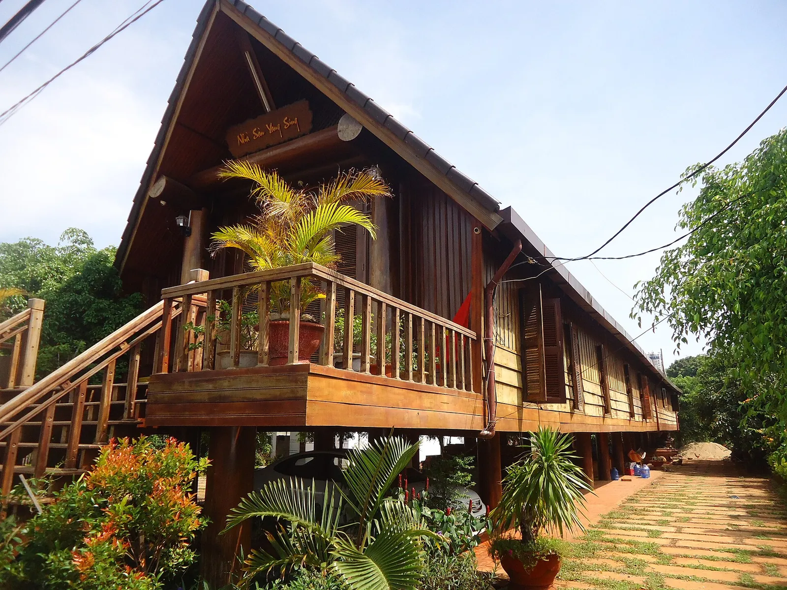Wooden Ede longhouse on stilts with a carved stair and balcony at Ako Dhong village