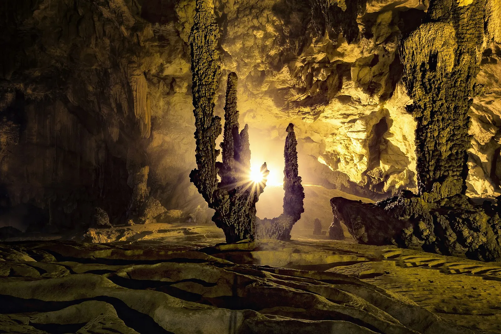 Lit stalactites and stalagmites in a large chamber of Nguom Ngao Cave