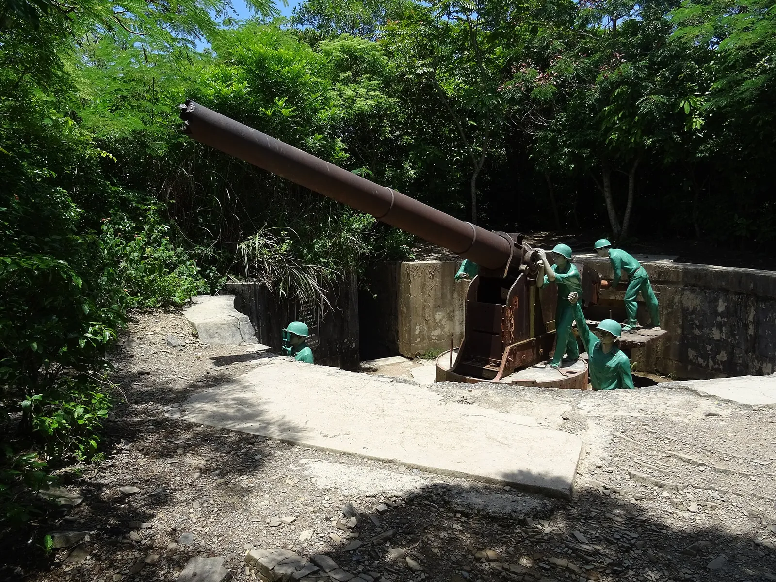 An old artillery gun with green soldier figures in a concrete emplacement at Cannon Fort, Cat Ba