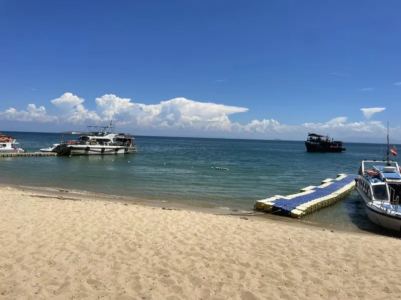 Sandy beach on the Cham Islands with tour boats and a floating jetty in calm blue water